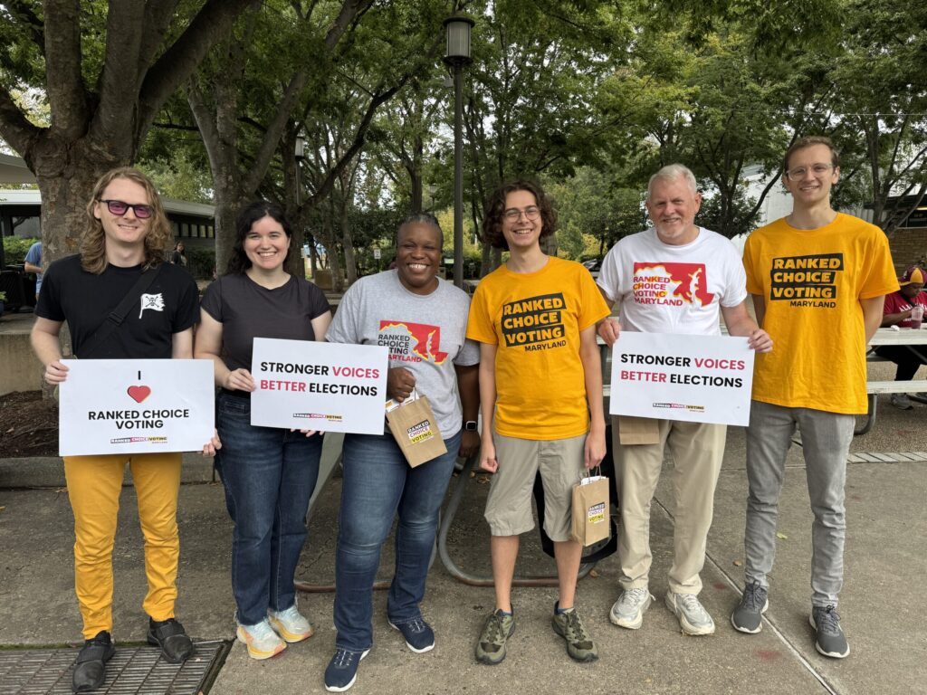 Six RCV Maryland volunteers holding Stronger Voices Better Elections signs at an outdoor event