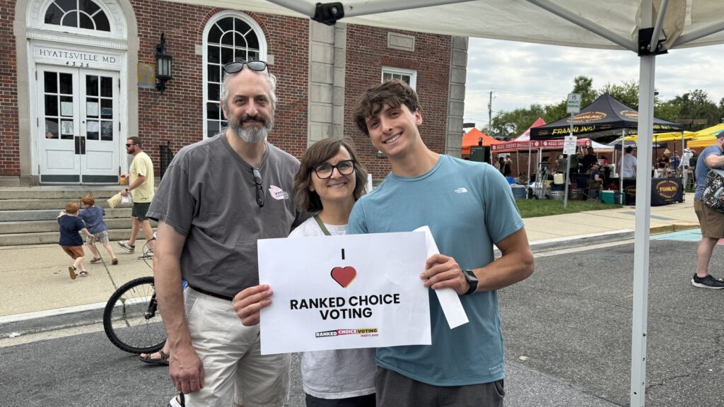 Three RCV Maryland supporters holding an I Love Ranked Choice Voting sign in front of Hyattsville City Hall